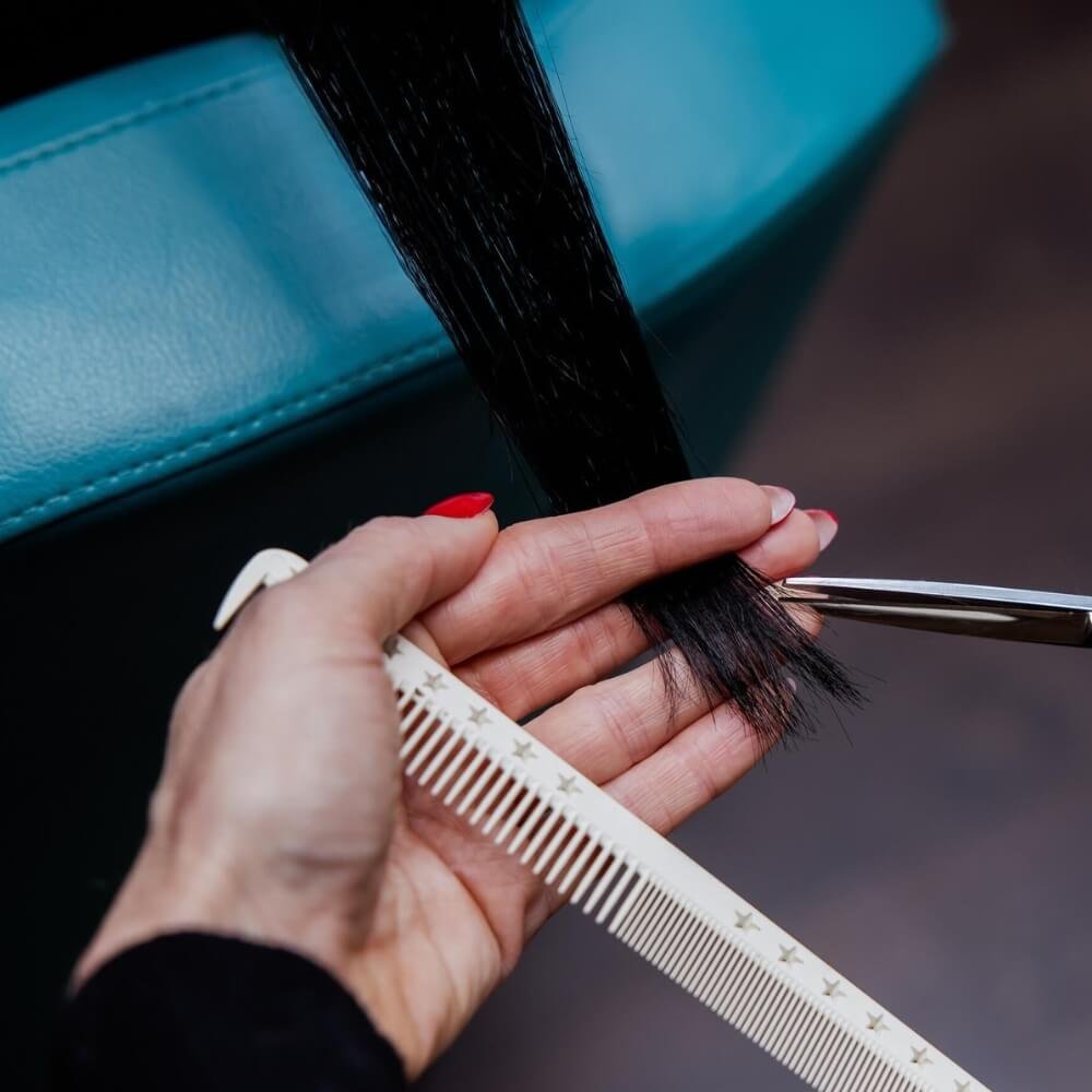 Professional hair stylist cutting tape hair extensions